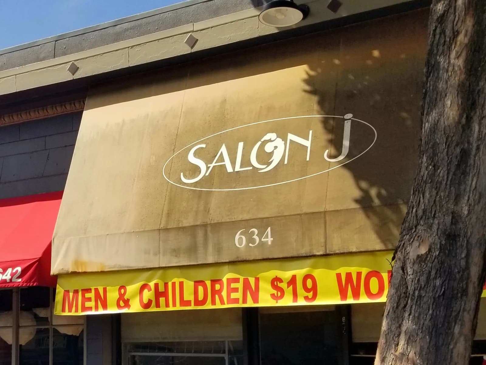 The sun-faded Salon J awning above 634 Irving Street, with the red-on-yellow price banner beneath it